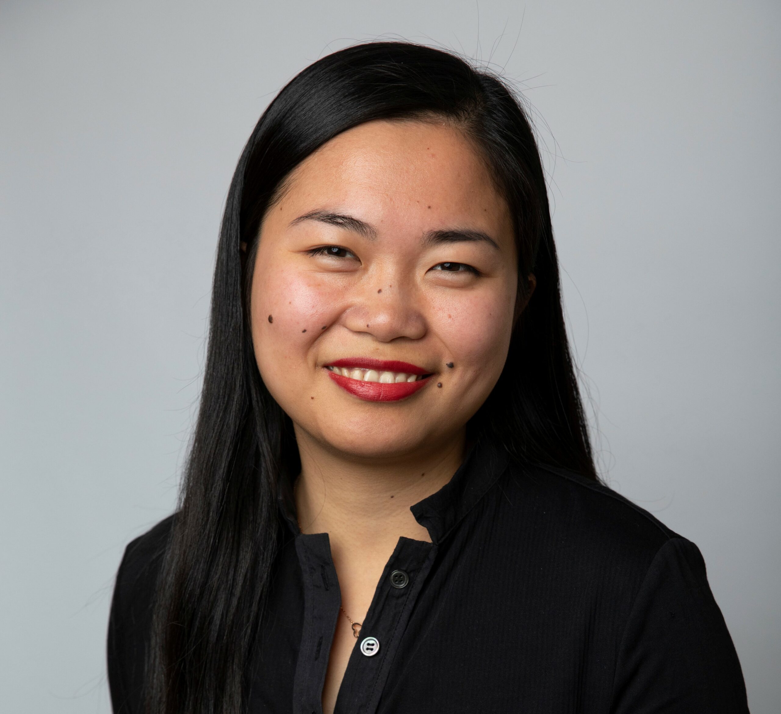 Q. Jane Zhao in a black collared top in front of a gray background.